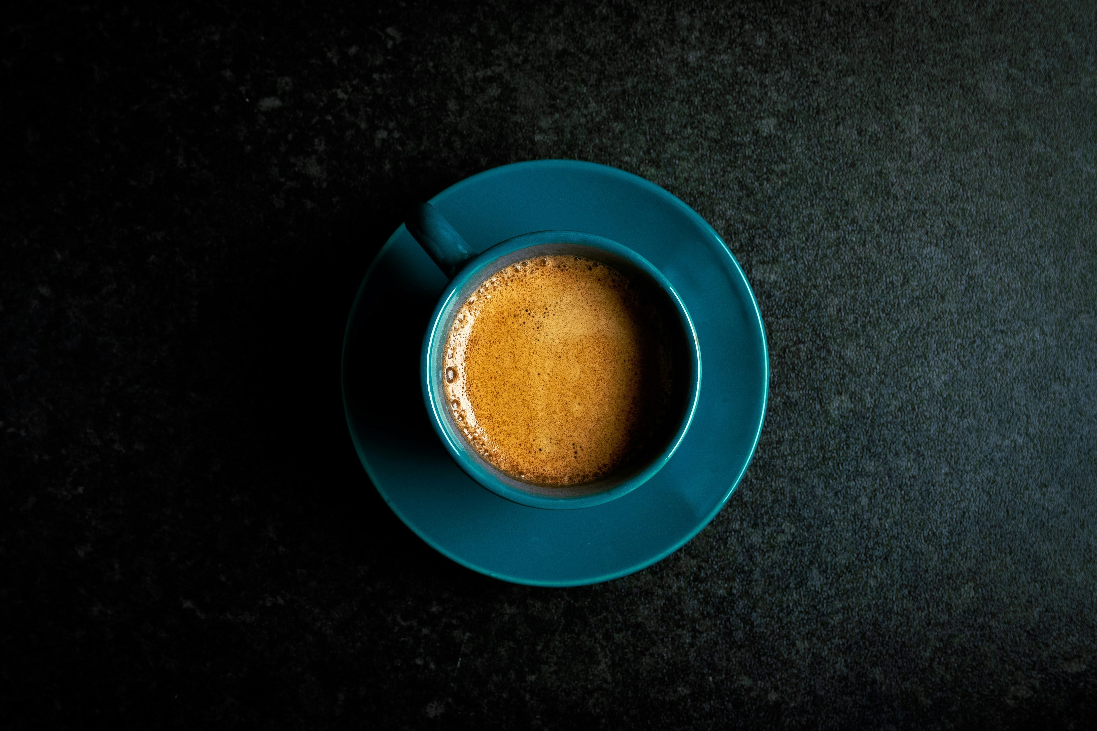Overhead view of a freshly roasted small-batch specialty coffee in a teal cup on a dark background — Wonder Waves Coffee