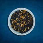 Close-up of Tropical Tides loose-leaf Mango black tea tea in a white bowl on a blue background by Wonder Waves Coffee