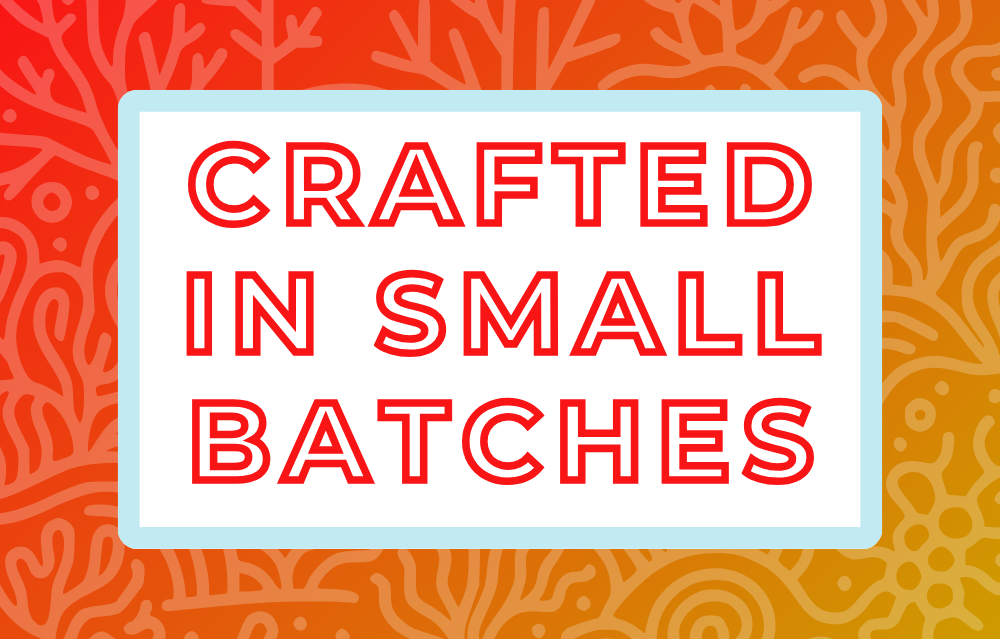 Text 'Crafted in Small Batches' on a white background, surrounded by a soft blue frame and a vibrant red and orange coral-themed backdrop, highlighting the artisan and small-batch blending process for artisan tea
