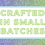 Text 'Crafted in Small Batches' on a white background, surrounded by a soft blue frame and a light purple and green coral-themed backdrop, highlighting the artisan and small-batch blending process for artisan tea