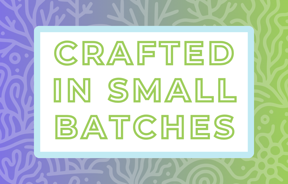 Text 'Crafted in Small Batches' on a white background, surrounded by a soft blue frame and a light purple and green coral-themed backdrop, highlighting the artisan and small-batch blending process for artisan tea