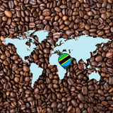 World map overlay on a bed of roasted coffee beans with a Tanzania flag marker highlighting the coffee’s origin in East Africa