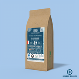 Bali Blue Indonesia whole bean coffee packaging with a rustic kraft bag design, featuring a deep teal ocean-themed label with a hibiscus flower illustration, coffee roast icons, and the ‘Single Origin’ label. Includes branding for Wonder Waves Coffee, emphasizing its medium-dark roast and eco-friendly packaging.