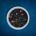 Close-up of Paradise Plunge loose-leaf Peach black tea tea in a white bowl on a blue background by Wonder Waves Coffee