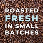 Close-up of roasted coffee beans with the text ‘Roasted Fresh in Small Batches’ overlaying the image, emphasizing the freshness and craftsmanship of the coffee