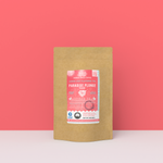 Paradise Plunge Peach black tea packaging with a rustic kraft pouch design, featuring a coral-pink ocean-themed label with a floral burst illustration, flavor notes, and the ‘Artisan Tea’ label. Includes branding for Wonder Waves Coffee, highlighting its rosy, sweet, and mild character and eco-conscious packaging.