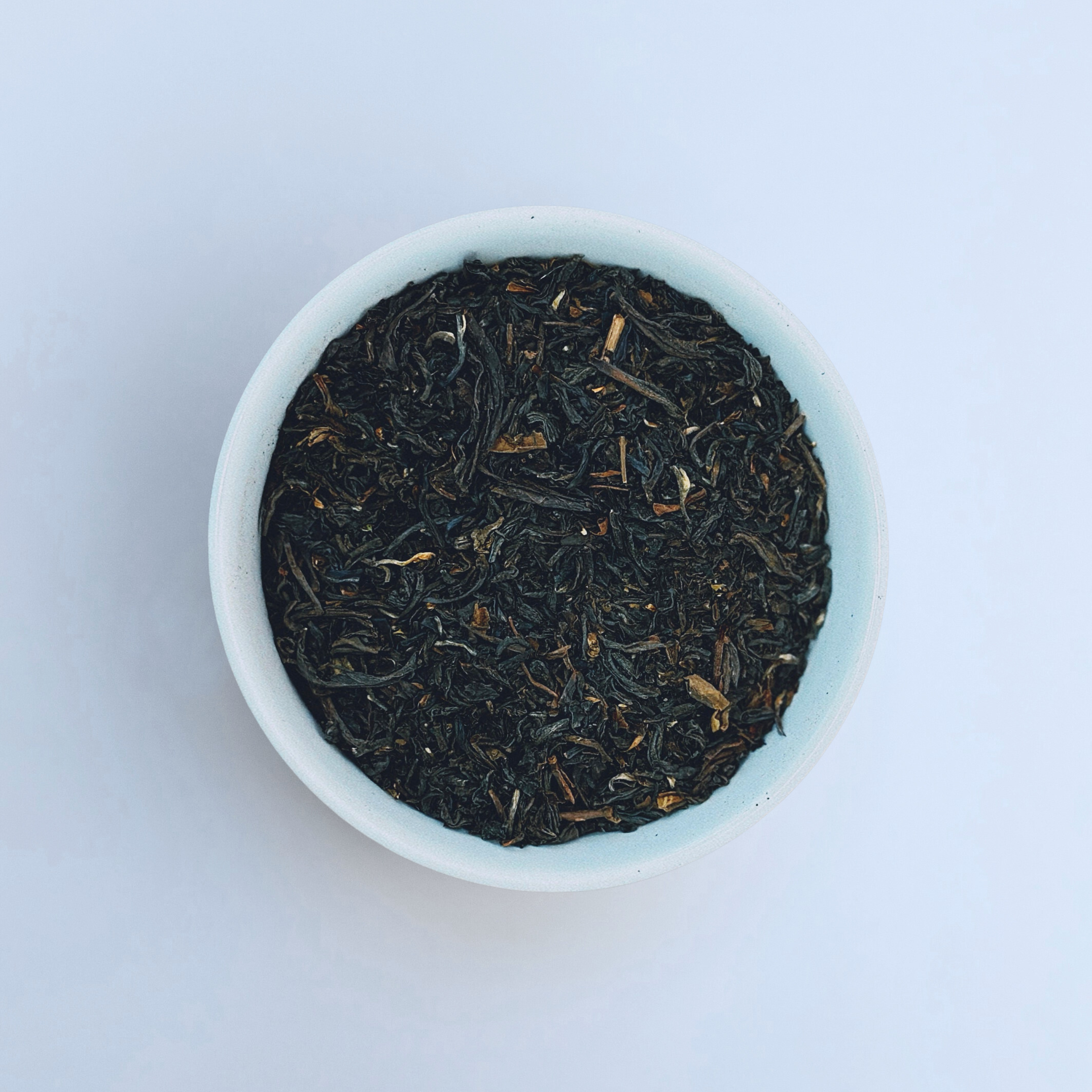 Close-up of Mighty Monarch English Breakfast loose-leaf black tea in a white bowl on a white background by Wonder Waves Coffee