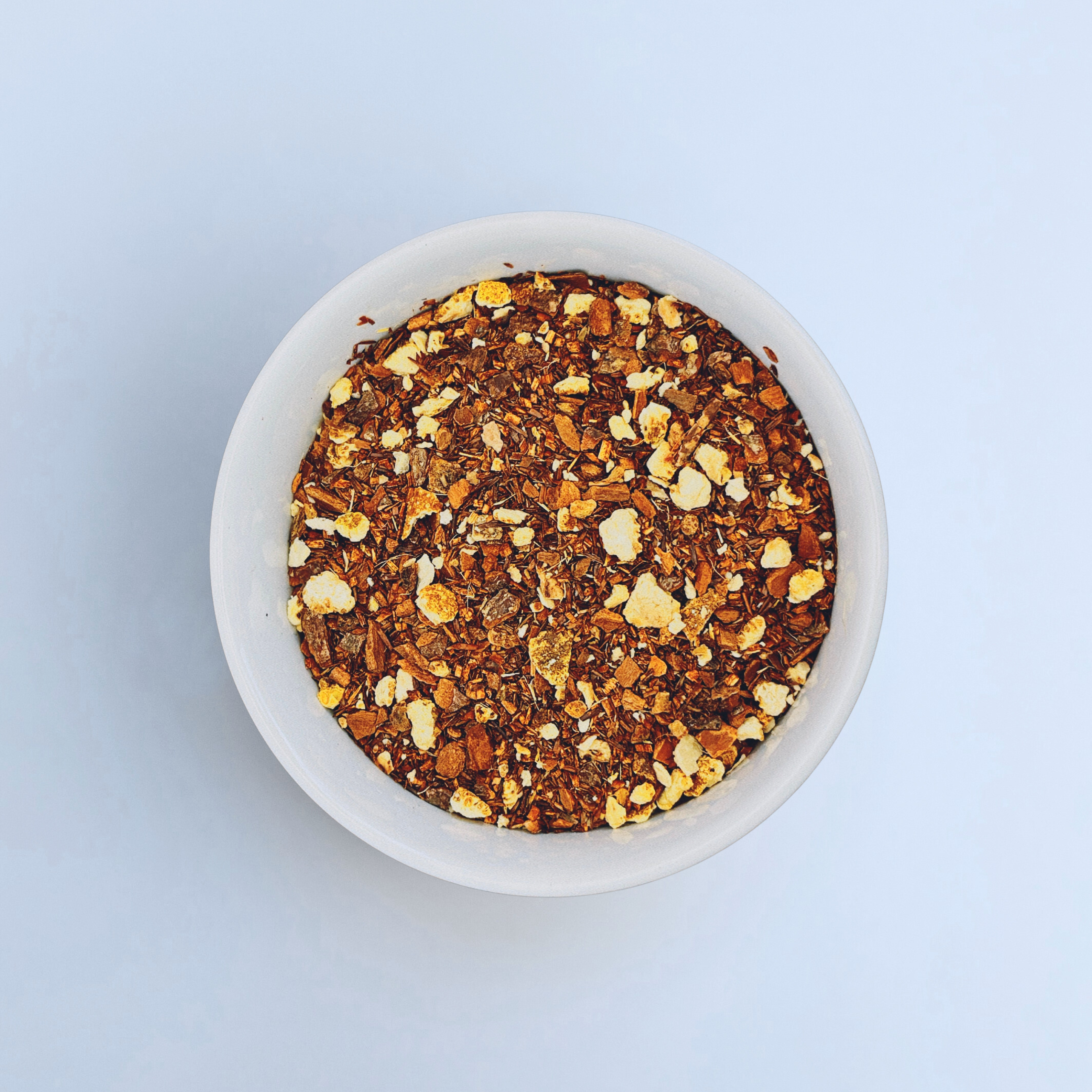 Close-up of Sunset Spice loose-leaf Apple Cider Rooibos caffeine-free tea in a white bowl on a white background by Wonder Waves Coffee