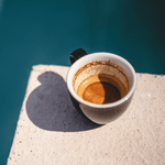 Italian espresso cup with Italian espresso on a stone table with an ocean blue background, capturing the essence of Marea Magnifica Italian Roast