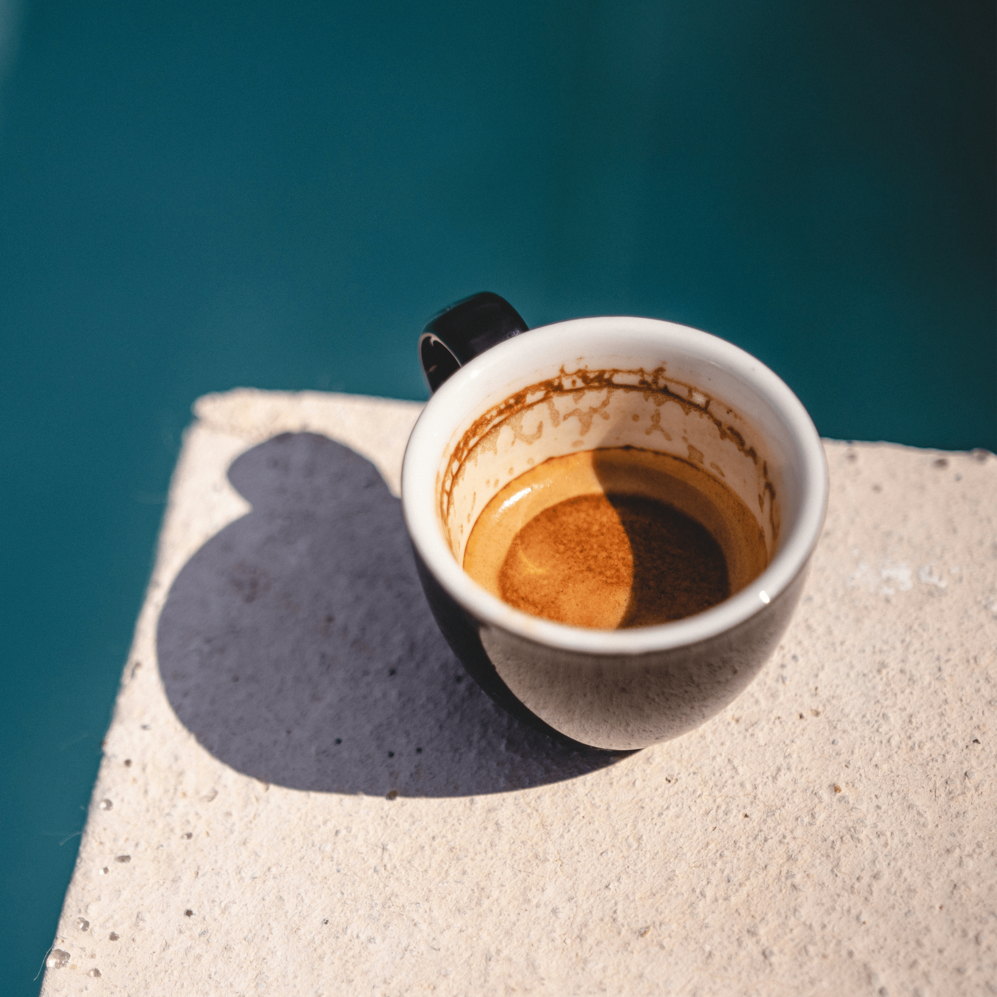 Italian espresso cup with Italian espresso on a stone table with an ocean blue background, capturing the essence of Marea Magnifica Italian Roast