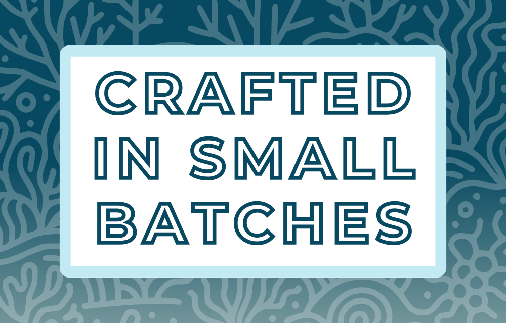 Text 'Crafted in Small Batches' on a white background, surrounded by a soft blue frame and a misty and deep blue coral-themed backdrop, highlighting the artisan and small-batch blending process for artisan tea