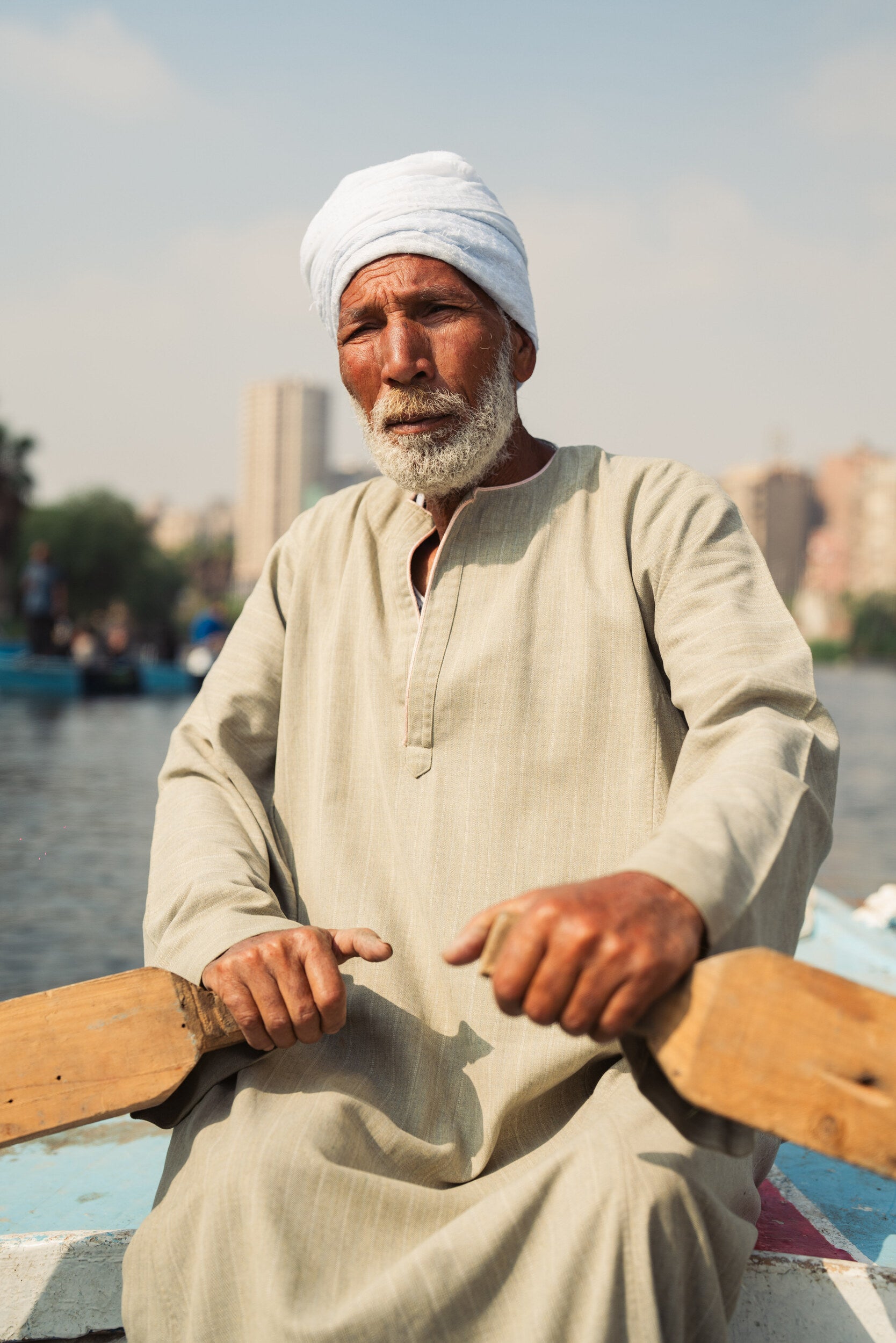 Man in traditional dress rowing a wooden boat on the Nile River