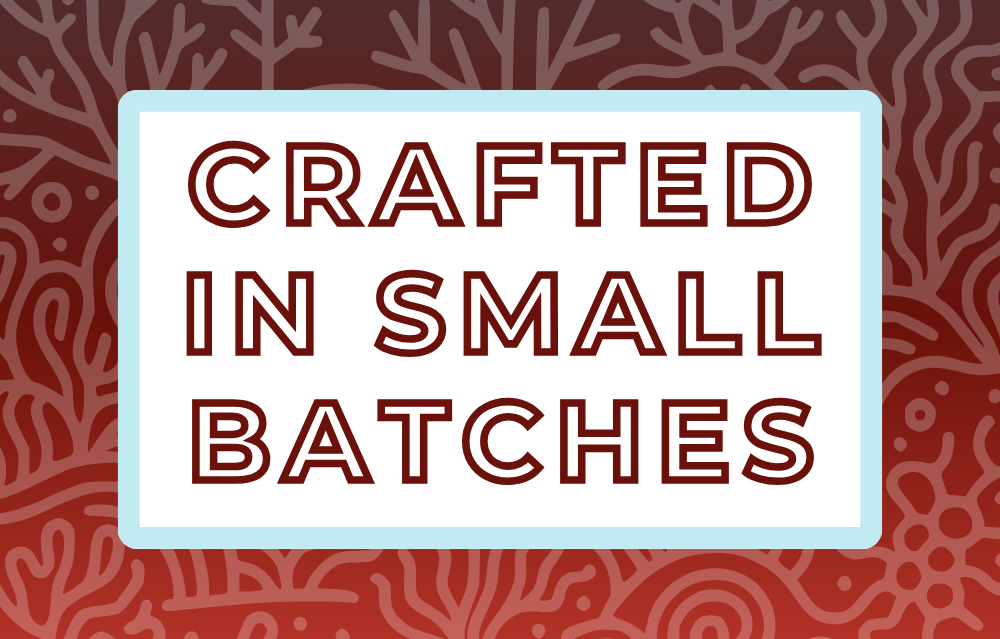 Text 'Crafted in Small Batches' on a white background, surrounded by a soft blue frame and a deep red coral-themed backdrop, highlighting the artisan and small-batch blending process for artisan tea