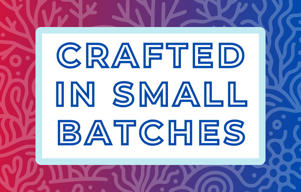 Text 'Crafted in Small Batches' on a white background, surrounded by a soft blue frame and a red and blue coral-themed backdrop, highlighting the artisan and small-batch blending process for artisan tea