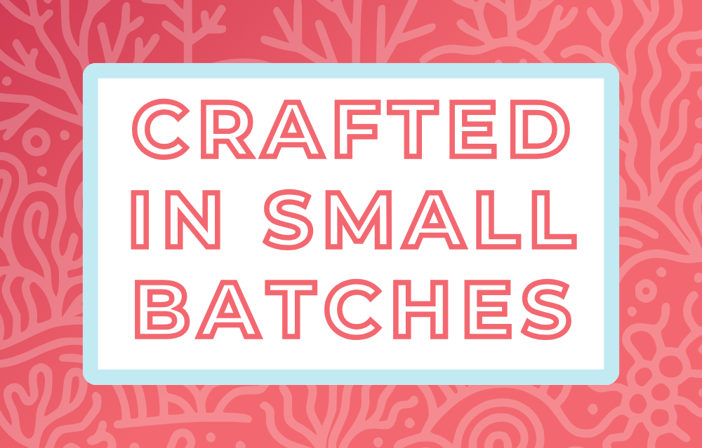 Text 'Crafted in Small Batches' on a white background, surrounded by a soft blue frame and a coral-pink and coral-themed backdrop, highlighting the artisan and small-batch blending process for artisan tea