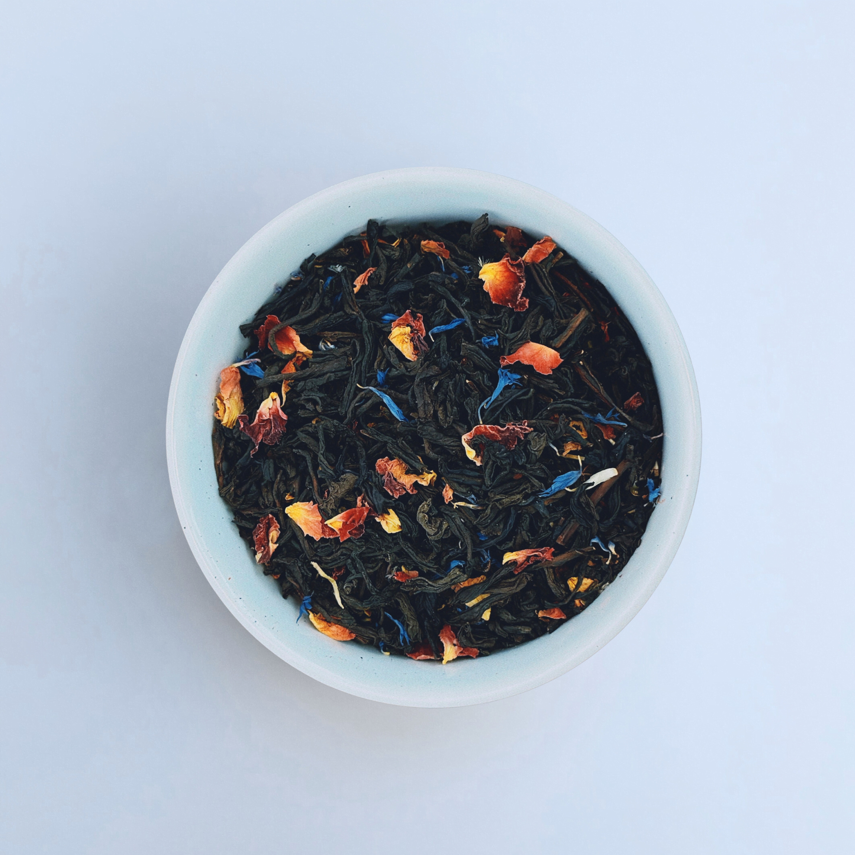 Paradise Plunge Peach loose leaf black tea in white bowl close-up by Wonder Waves Coffee featuring smooth peach notes and a gentle fruity finish