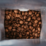 Close-up view looking into a open 12oz retail bag of premium roasted coffee beans, showcasing the fresh, uniform roast