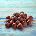 Whole hazelnuts on a rustic wooden surface highlighting the warm, nutty flavor notes of Wonder Waves Coffee Seabreeze Sizzle hazelnut flavored coffee.