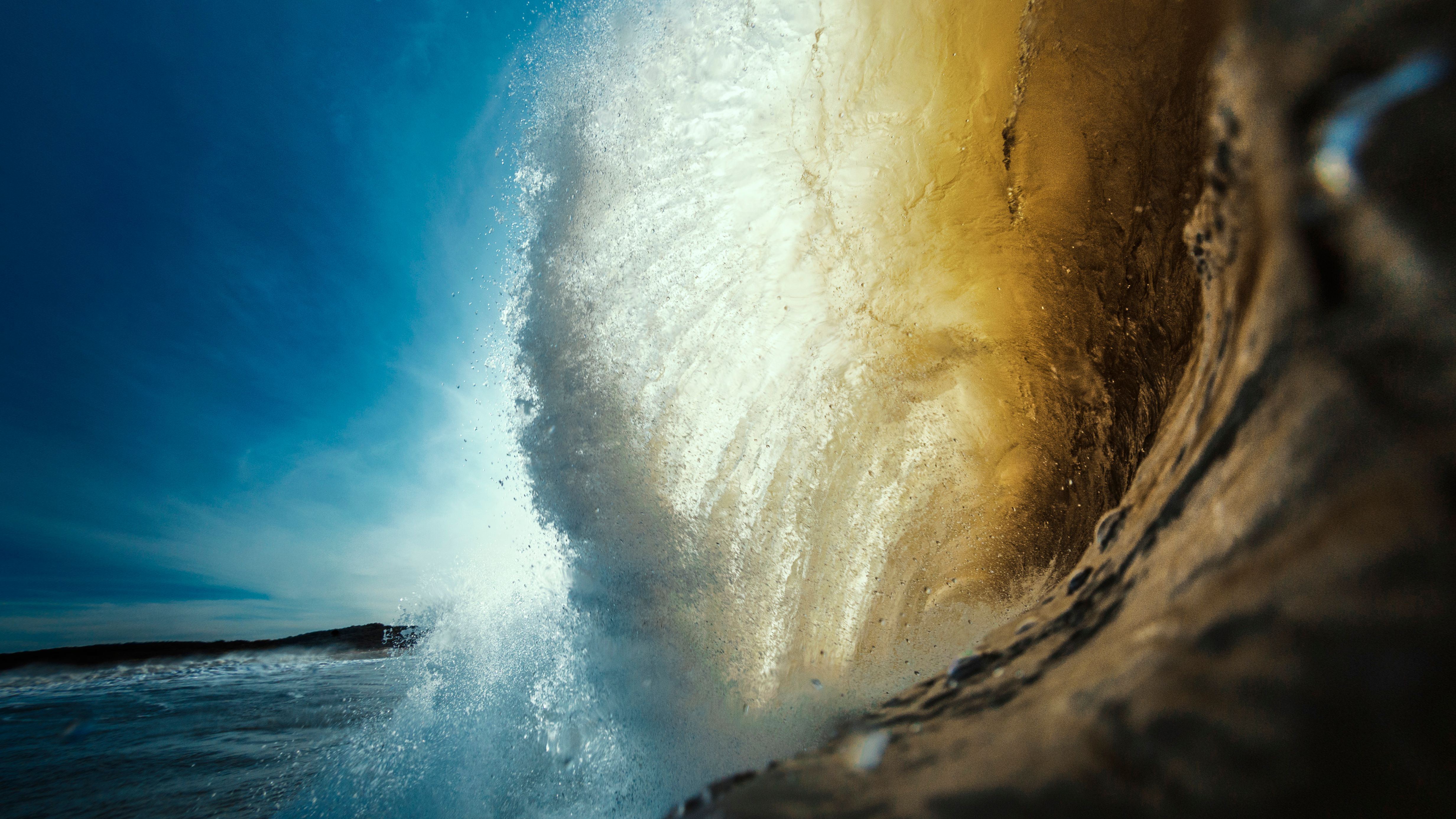Golden barreling ocean wave breaking against blue sky, representing Wonder Waves Coffee's ocean-driven mission