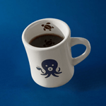 Wonder Waves Coffee white ceramic diner mug filled with black coffee featuring Ollie the Octopus on a deep navy blue background with a sea turtle detail visible inside the rim